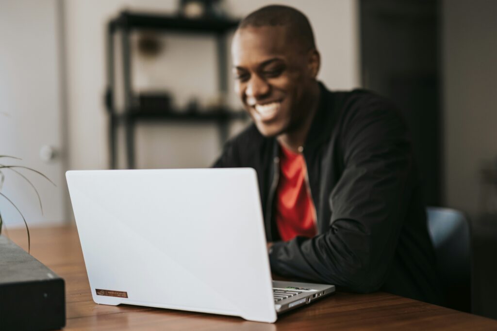 A man is smiling while working on his laptop