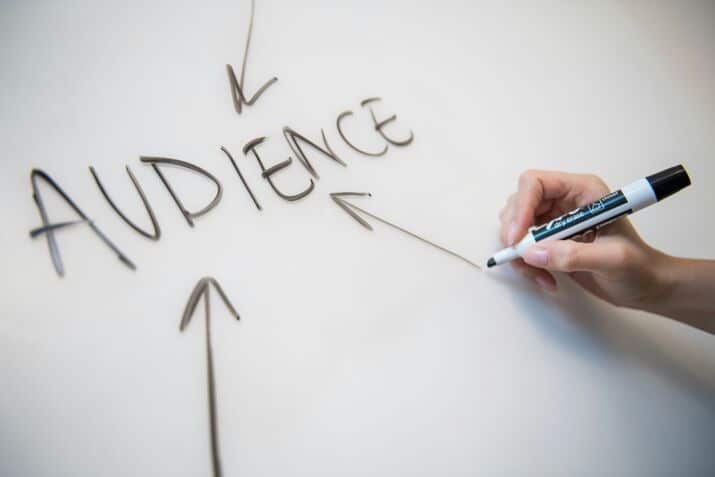 a man writing the word audience on a board