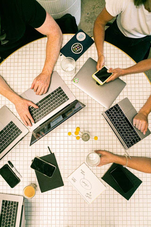 a group of people with their MacBooks