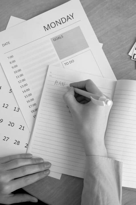 a man writing the word plan on paper